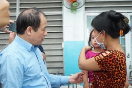 Cục Trưởng Cục Y tế Dự phòng Trần Đắc Phu hỏi thăm bệnh nhân mắc sởi đang điều trị tại Bệnh viện Bệnh Nhiệt đới Thành phố Hồ Chí Minh. (Ảnh: Đinh Hằng/TTXVN)