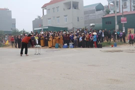 Người dân thôn Trung Nguyên, xã Trung Nguyên tập trung tại nơi xảy ra tai nạn vụ xe khách lao vào đoàn người đưa tang để làm lễ, cầu nguyện... (Ảnh: Nguyễn Trọng Lịch/TTXVN)
