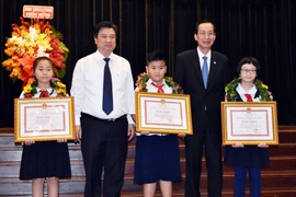 Thứ trưởng Bộ Giáo dục và Đào tạo Nguyễn Hữu Độ và Phó Chủ tịch Thường trực Ủy ban Nhân dân Thành phố Hồ Chí Minh Lê Thanh Liêm tặng bằng khen cho học sinh. (Ảnh: Thu Hoài/TTXVN)