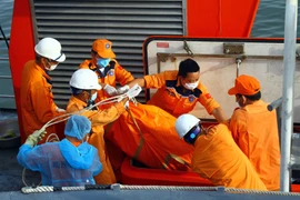 Lực lượng chức năng đưa thi thể hai thuyền viên tàu cá NA 95899 TS lên bờ, sáng 18/7/2019. (Ảnh: Tá Chuyên/TTXVN)