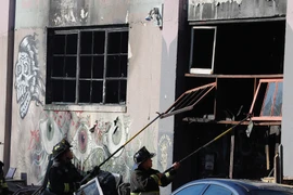 Lính cứu hoả don dẹp tại hiện trường vụ cháy. (Nguồn: EPA/TTXVN)