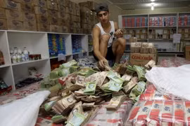 Một người đàn ông đếm những đồng tiền bolivar trong một cửa hàng ở Brazil. (Nguồn: Reuters)