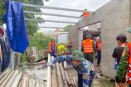 Bộ đội Biên phòng tỉnh Thừa Thiên-Huế phối hợp với chính quyền địa phương hỗ trợ các gia đình bị thiệt hại lợp lại, gia cố mái nhà. (Ảnh: TTXVN phát)