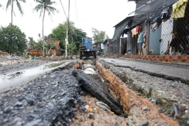 Trận lũ lớn xảy ra tại thị trấn Hiệp Phước, huyện Nhơn Trạch, tỉnh Đồng Nai, khiến mặt đường của một số tuyến đường bị bong tróc, từng mảng nhựa đường bị nước cuốn trôi tới nhiều vị trí khác nhau. (Ảnh: Lê Xuân/TTXVN)
