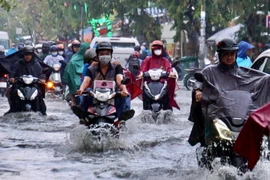 Người dân vượt dòng nước ngập trên đường Tô Ngọc Vân, thành phố Thủ Đức, Thành phố Hồ Chí Minh. (Ảnh: Hồng Giang/TTXVN)