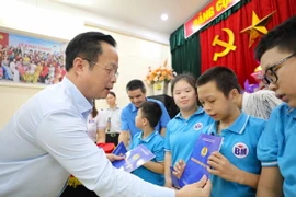 Giám đốc Sở Giáo dục và Đào tạo Hà Nội Trần Thế Cương trao tặng các món quà tới học sinh của 3 ngôi trường chuyên biệt. (Ảnh: Thanh Tùng/TTXVN)