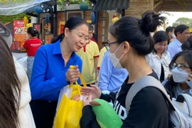 Bí thư Thành Đoàn Thành phố Hồ Chí Minh Phan Thị Thanh Phương trao quà Tết cho sinh viên, người lao động trước giờ lên xe. (Ảnh: Hồng Giang/TTXVN)