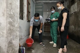 Nhân viên y tế quận Hoàng Mai hướng dẫn người dân vệ sinh môi trường, xử lý khu vực muỗi có thể phát triển sinh sản tại hộ gia đình. (Ảnh: Minh Quyết/TTXVN)