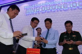 Lãnh đạo tỉnh Bình Dương tải app "Bình Dương số" cài về điện thoại thông minh để theo dõi mọi hoạt động của xã hội, kinh tế và các tiện ích khác. (Ảnh: Chí Tưởng/TTXVN)