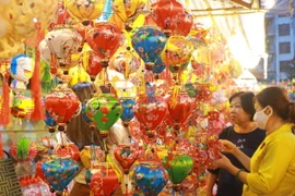 Người dân lựa chọn các mẫu lồng đèn về trang trí cho căn nhà. (Ảnh: Thu Hương/TTXVN)