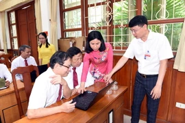 Bà Đặng Thúy Vân, Chủ tịch UBND phường Việt Hưng (áo đỏ) hướng dẫn các Bí thư chi bộ sử dụng phần mềm. (Ảnh: TTXVN)