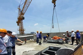 Lực lượng cưỡng chế cắt sàn mái tầng 18 công trình 8B Lê Trực, Hà Nội. (Ảnh: Mạnh Khánh/TTXVN)