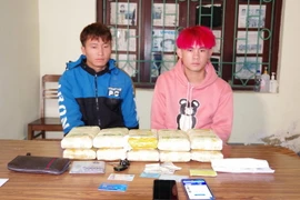 Đối tượng Thào A Chống (trái) và Vàng A Cử (phải) cùng tang vật tại cơ quan điều tra. (Ảnh: TTXVN phát)