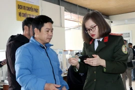 Cán bộ Phòng quản lý Xuất nhập cảnh hướng dẫn người dân làm thủ tục hộ chiếu trực tuyến. (Ảnh: Công Tường/TTXVN)