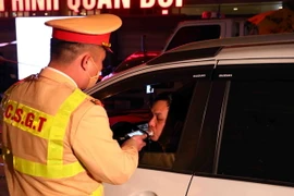 Cán bộ, chiến sỹ thuộc tổ công tác Y6/141 kiểm tra nồng độ cồn 1 tài xế ô tô tại đường Xã Đàn-Nam Đồng. (Ảnh: Phạm Kiên/TTXVN)