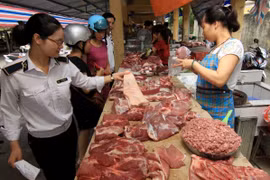 Nhân viên thú y kiểm tra hộ kinh doanh thịt lợn tại chợ. (Ảnh: Vũ Sinh/TTXVN)