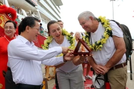 Chủ tịch UBND tỉnh Quảng Ninh Cao Tường Huy (trái) tặng quà lưu niệm cho vợ chồng vị khách quốc tế thứ 3 triệu đến Quảng Ninh. (Ảnh: Văn Đức/TTXVN)