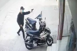 Tên cướp dùng súng uy hiếp nhân viên, người dân và bảo vệ. (Nguồn: Ảnh cắt từ clip)