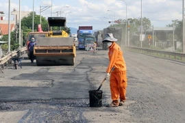 Công nhân và thiết bị cơ giới được các nhà thầu huy động để sửa chữa hư hỏng mặt đường Quốc lộ 1. (Ảnh: Xuân Triệu/TTXVN)