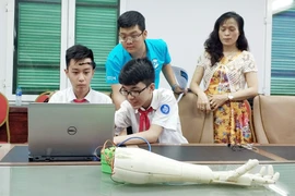 Hai học sinh lớp 8 Trường THCS Trưng Vương (Hà Nội) trình diễn điều khiển cánh tay robot bằng suy nghĩ tại họp báo STEM 2018. (Ảnh: T.H/Vietnam+)