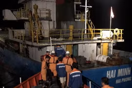 Sau khi được Tàu SAR27-01 cứu nạn do rơi xuống biển, ba thuyền viên (áo xanh đen) về lại tàu Hải Minh 36. (Ảnh: TTXVN phát)