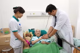 Nhân viên y tế thăm hỏi tặng hoa chúc mừng cụ bà đã khỏe lại chuẩn bị xuất viện. (Ảnh: Kiều Oanh/Vietnam+)