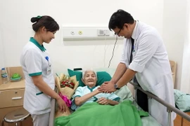 Nhân viên y tế thăm hỏi tặng hoa chúc mừng cụ bà đã khỏe lại chuẩn bị xuất viện. (Ảnh: Kiều Oanh/Vietnam+)
