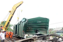 Cẩu chuyên dụng đưa toa tàu bị hư hỏng ra khỏi đường ray. (Ảnh: Đỗ Trưởng/TTXVN)