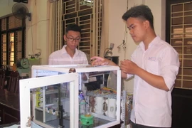 Em Giang Quốc Hoàn và Đỗ Hữu Toàn kiểm tra mô hình robot thí nghiệm hóa học. (Ảnh: Thùy Dung/TTXVN)