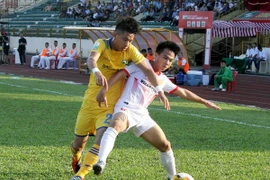 Pha tranh chấp bóng của cầu thủ Sông Lam Nghệ An (áo vàng) và cầu thủ Nam Định (áo trắng). (Ảnh: Tá Chuyên/TTXVN)