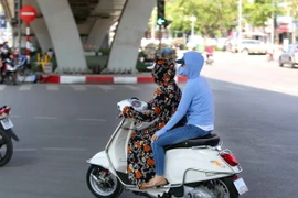 Người dân ra đường với trang phục kín mít để tránh nắng. (Ảnh: Thành Đạt/TTXVN)