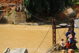 Hàng tiếp tế được vận chuyển bằng cáp treo qua chiếc cầu đã bị sập đến hai thôn Sủng Hoảng 1, Sủng Hoảng 2. (Ảnh: Hương Thu/TTXVN)