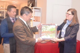 Ông Nguyễn Tuấn Phong tặng bà Sandra Smith và Đảng Cộng sản Marxist Leninist Canada bức tranh về Hà Nội. (Ảnh: Trường Giang/TTXVN)