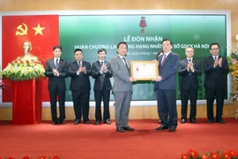 Ông Đinh Tiến Dũng, Bộ trưởng Bộ Tài chính thừa ủy quyền của Chủ tịch nước trao Huân chương Lao động hạng Nhất cho HNX. (Ảnh: Tuấn Anh/TTXVN)