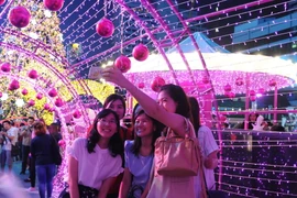 Du khách chụp ảnh tại một trung tâm mua sắm ở thủ đô Bangkok. (Nguồn: THX/TTXVN)