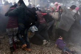 Người di cư chạy trốn hơi cay do cảnh sát Macedonia sử dụng nhằm ngăn dòng người bạo động đang tìm cách phá hàng rào biên giới. (Nguồn: AFP/TTXVN)
