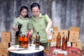 Tiêu hủy rượu ngoại không rõ nguồn gốc xuất xứ. (Ảnh : Bích Huệ/TTXVN)