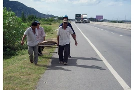 Đưa nạn nhân ra khỏi hiện trường vụ tai nạn. (Ảnh: Công Thử/TTXVN)