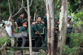 Lực lượng chức năng đang bàn giải pháp đưa thi thể các phi công xuống nùi. (Ảnh: Đoàn Mạnh Dương/TTXVN)