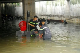 Các chiến sỹ Phòng cháy chữa cháy lắp đặt các ống hút lớn để bơm nước ra ngoài cứu xe. (Ảnh: Mạnh Linh/TTXVN) 