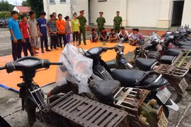 Các đối tượng tham gia đánh bạc, cùng tang vật tại cơ quan điều tra. (Ảnh: Thanh Tân/TTXVN)