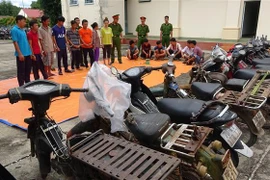 Các đối tượng tham gia đánh bạc, cùng tang vật tại cơ quan điều tra. (Ảnh: Thanh Tân/TTXVN)