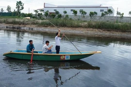 Lực lượng chức năng dùng thuyền để tìm cá sấu trên sông Cầu Đông. (Ảnh: Phan Quân/TTXVN)