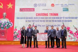 Ông Phạm Đức Ấn - Chủ tịch Hội đồng thành viên Agribank trao tặng quà của Agribank hỗ trợ hộ cận nghèo, đối tượng chính sách quận Hà Đông (Hà Nội) nhân dịp Tết Nguyên đán Giáp Thìn. (Ảnh: PV/Vietnam+)