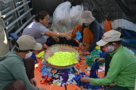 Những người lao động đang phân loại vải vụn. (Ảnh: Đinh Văn Nhiều/TTXVN) 