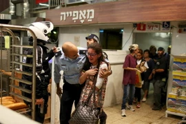 Binh sỹ Israel sơ tán người dân tại một siêu thị bên trong bến xe buýt trung tâm thành phố Jerusalem, sau khi cụ bà bị tấn công, ngày 14/10. (Nguồn: Reuters/TTXVN) 