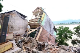Mưa lũ gây sạt lở tại khu vực tổ 25-26, phường Đồng Tiến theo hướng ngả ra sông Đà, tỉnh Hòa Bình làm nhiều ngôi nhà đổ sụp. (Ảnh: Quang Quyết/TTXVN)