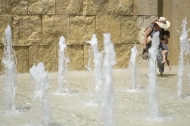 Người dân tránh nắng nóng bên vòi phun nước tại Rome, Italy. (Nguồn: AFP/TTXVN)