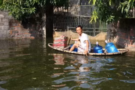 Người dân Chương Mỹ di chuyển bằng thuyền đi lấy lương thực và nước uống. (Ảnh: TTXVN)