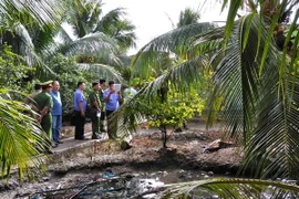 Lực lượng chức năng khám nghiệm hiện trường vụ án. (Ảnh: Nam Thái/TTXVN)